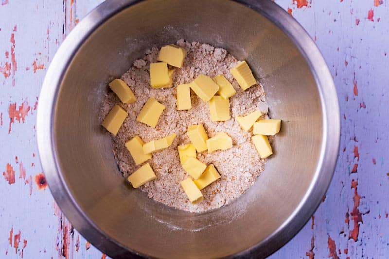 A mixing bowl with flour and cubes of butter.