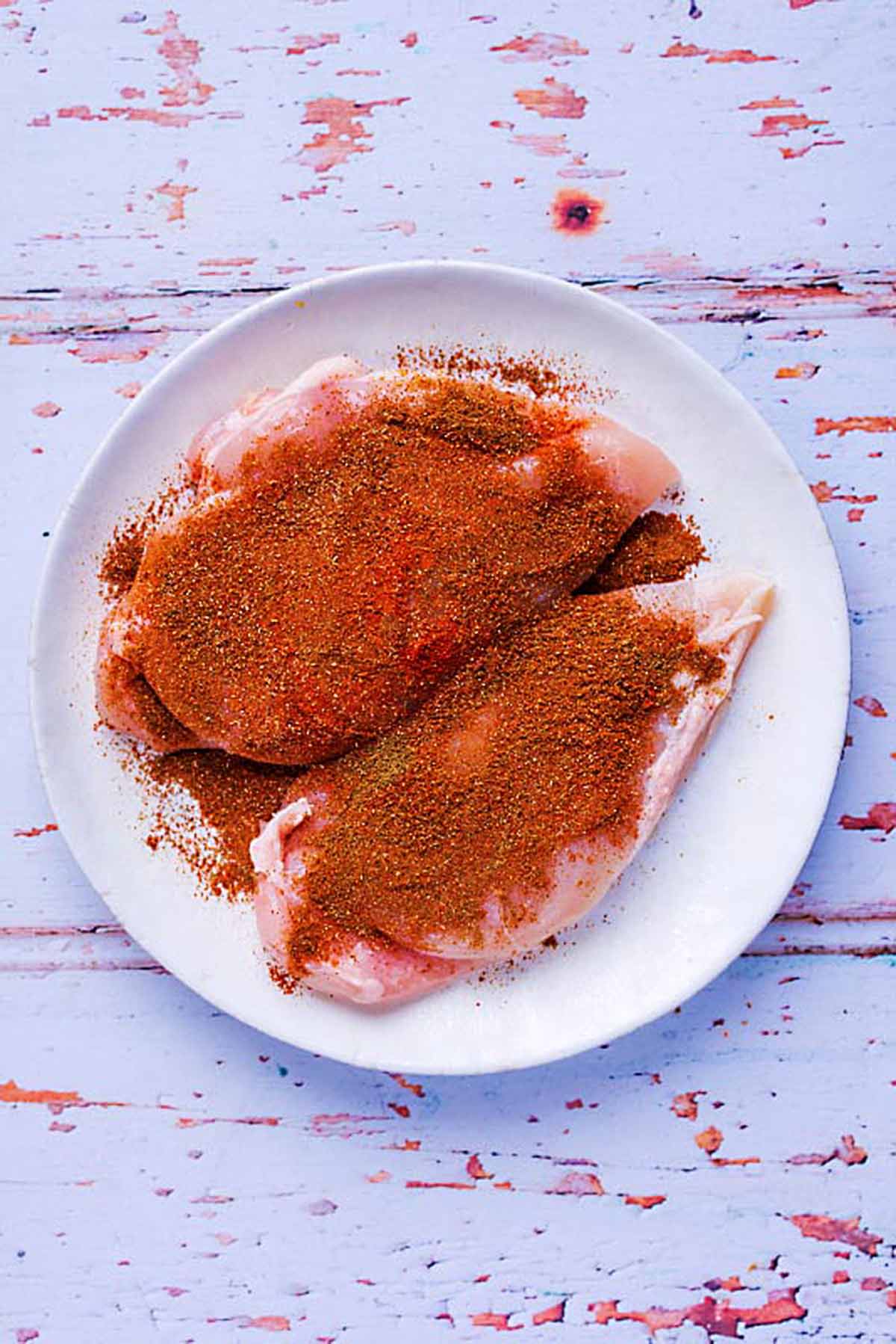 Two chicken breasts coated in Cajun seasoning on a plate.