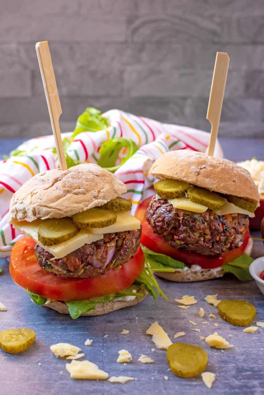 Two Beef Burgers in buns with tomato, cheese and pickles.