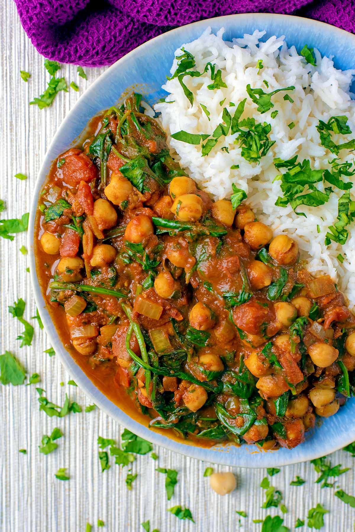 Chickpea and spinach curry on a blue plate with rice.