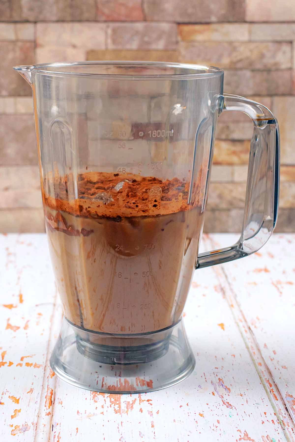 A blender jug containing all the ingredients for a frappuccino.