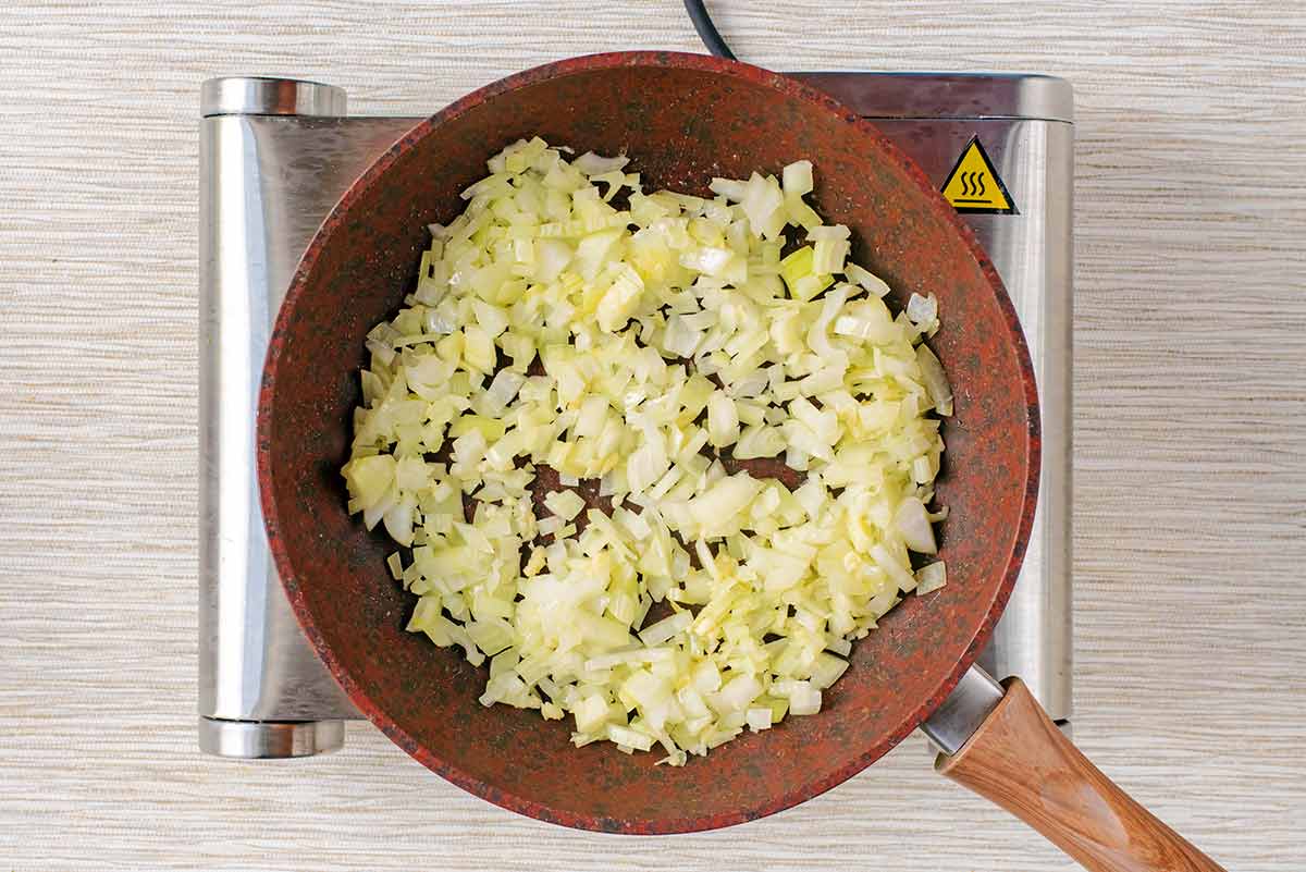 Chopped onions cooking in a frying pan.