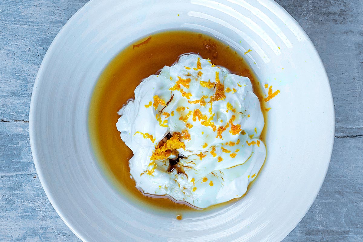 A bowl with yogurt, maple syrup, vanilla and orange zest in it