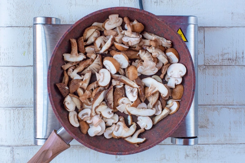 A frying pan full of sliced mushrooms.