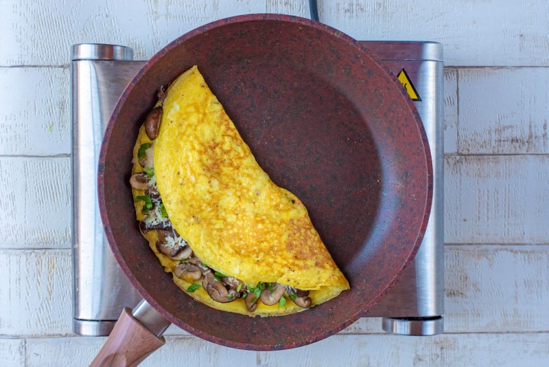 A frying pan containing a mushroom omelette folded in half.