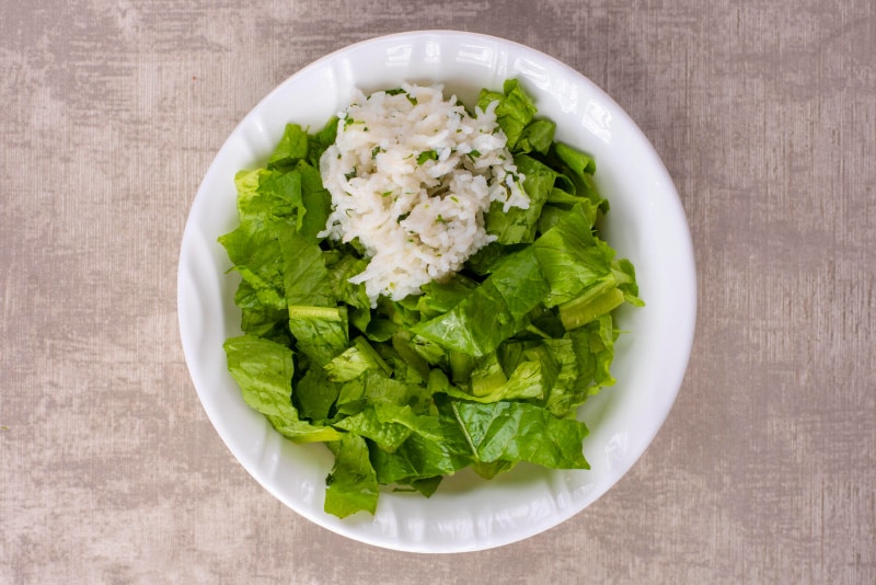 A white bowl containing shredded lettuce and white rice.