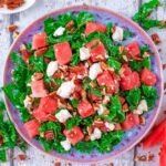 A plate of kale, watermelon and feta salad surrounded by watermelon slices.