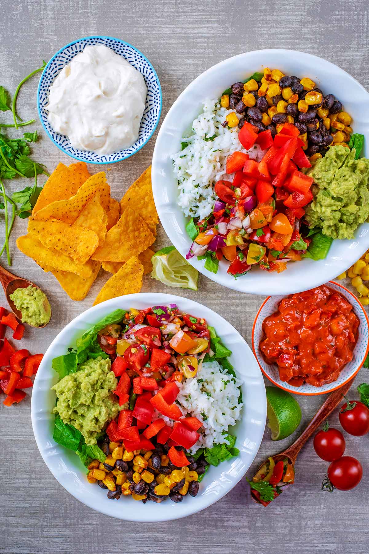 Two burrito bowls surrounded by burrito ingredients.