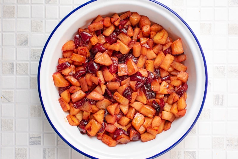 Cooked chopped apples and cherries in an oven dish.