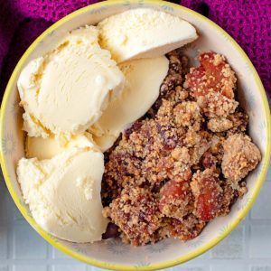 Apple and Cherry Crumble in a bowl with vanilla ice cream