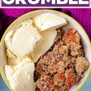 A bowl of apple and cherry crumble with a text title overlay.