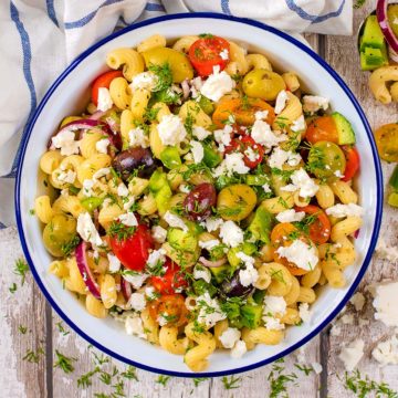 Greek pasta salad in a blue and white bowl.