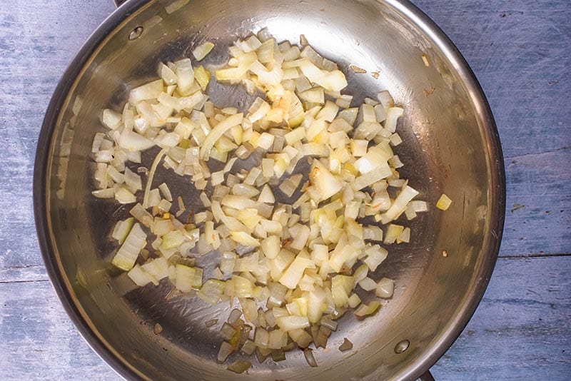 A large pan with chopped onions cooking in it.
