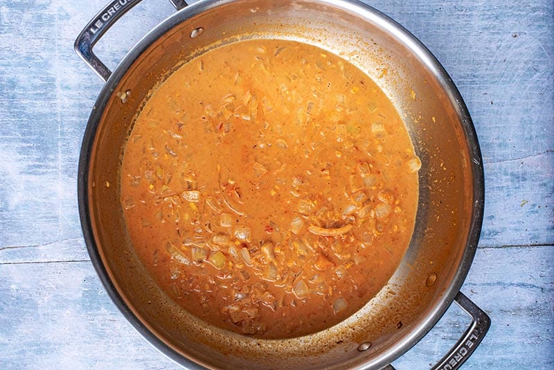A large pan with a curry sauce cooking in it.
