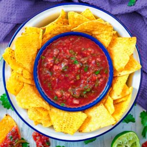 Restaurant style salsa in a bowl with some tortilla chips.