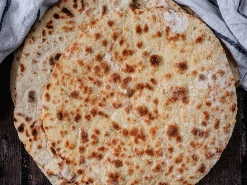 A stack of homemade flatbreads on a wooden surface.