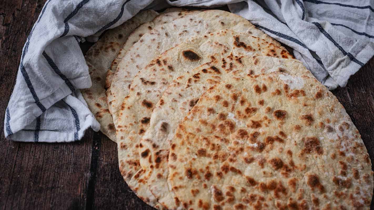 Six flatbreads in front of a striped towel.