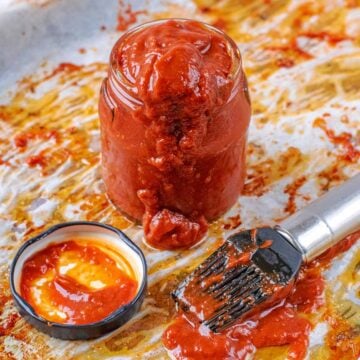 A small jar of healthy bbq sauce with a marinating brush in front of it.