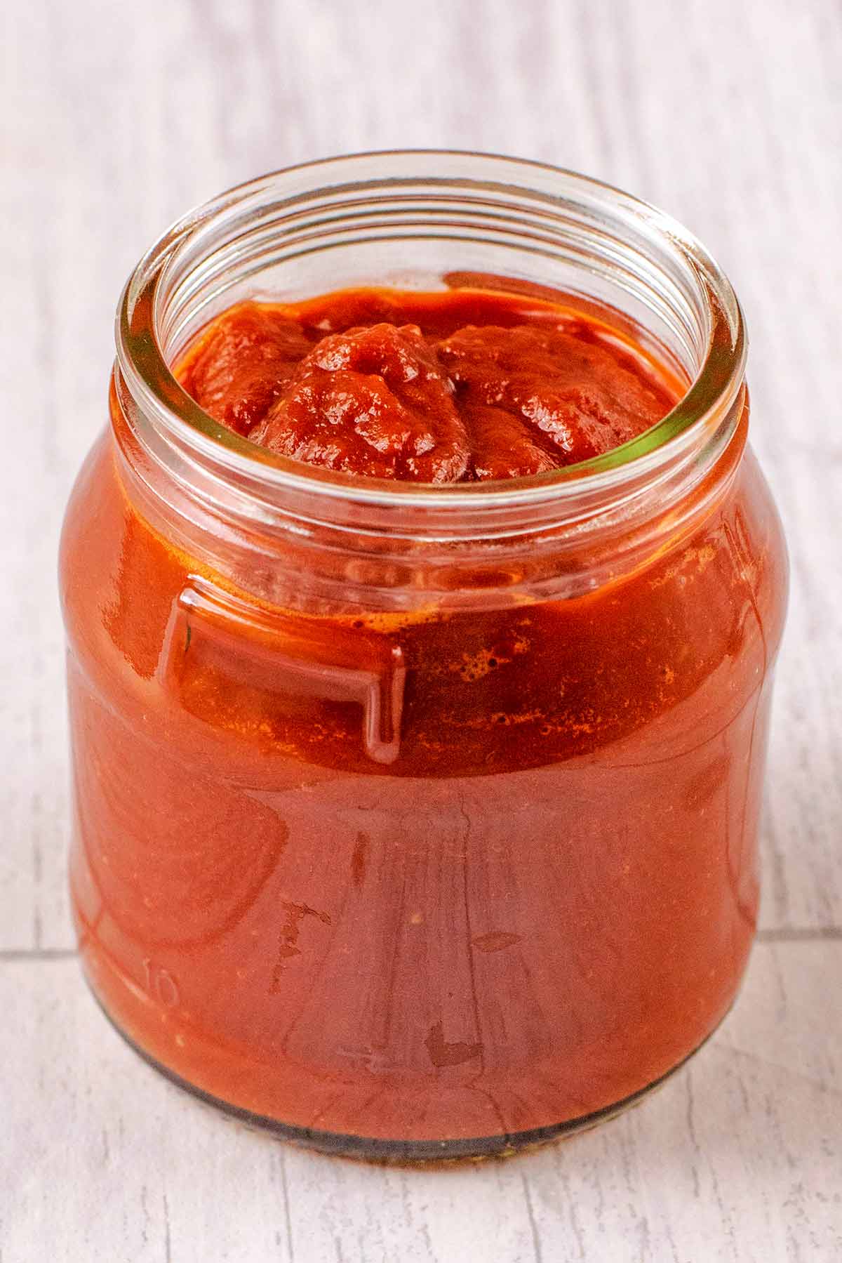 A jar of bbq sauce stood on a wooden surface.