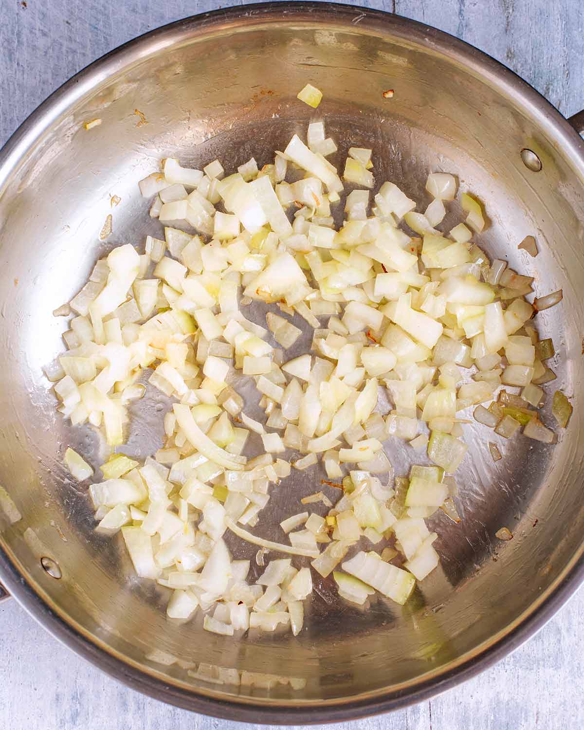 A large pan with chopped onions cooking in it.