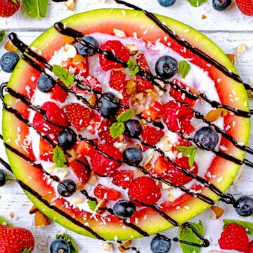 Watermelon fruit pizza topped with fruit and a drizzle of chocolate.