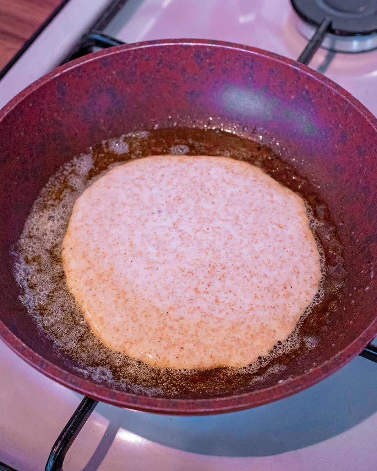 A frying pan with a pancake cooking in it.