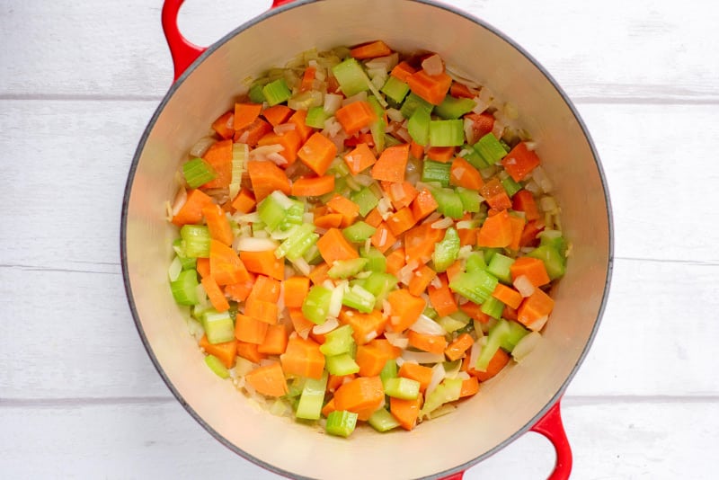 A large red pan with chopped celery and carrot.