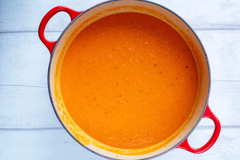 Blended Tomato and Red pepper soup in a large red pan.