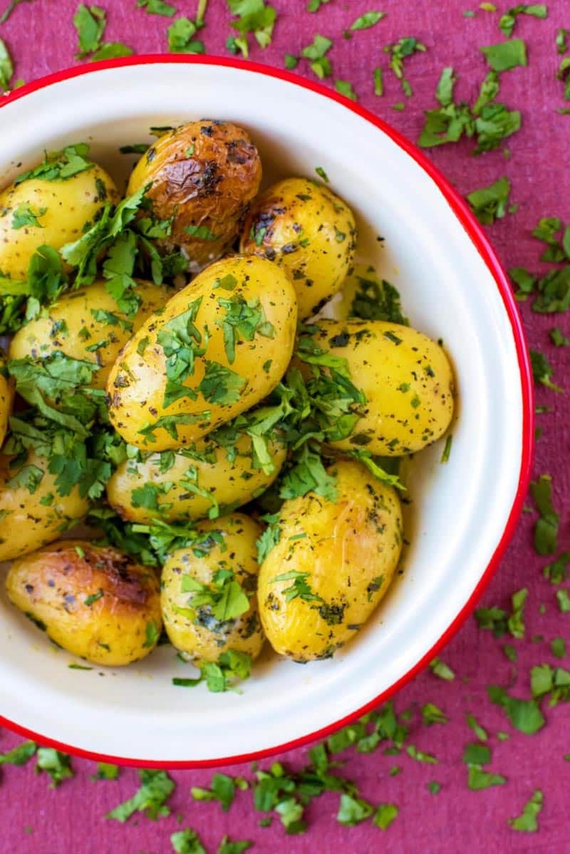 Roasted potatoes in a red rimmed bowl.