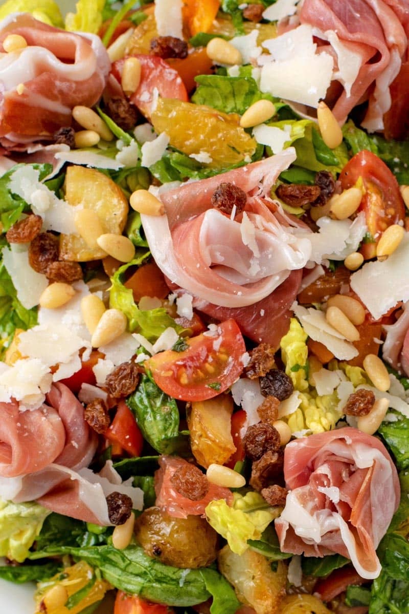A chopped salad of lettuce, tomatoes, potatoes, fruit, nuts and parma ham.