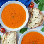 A bowl of Roasted Red Pepper and Tomato Soup with a slice of buttered bread