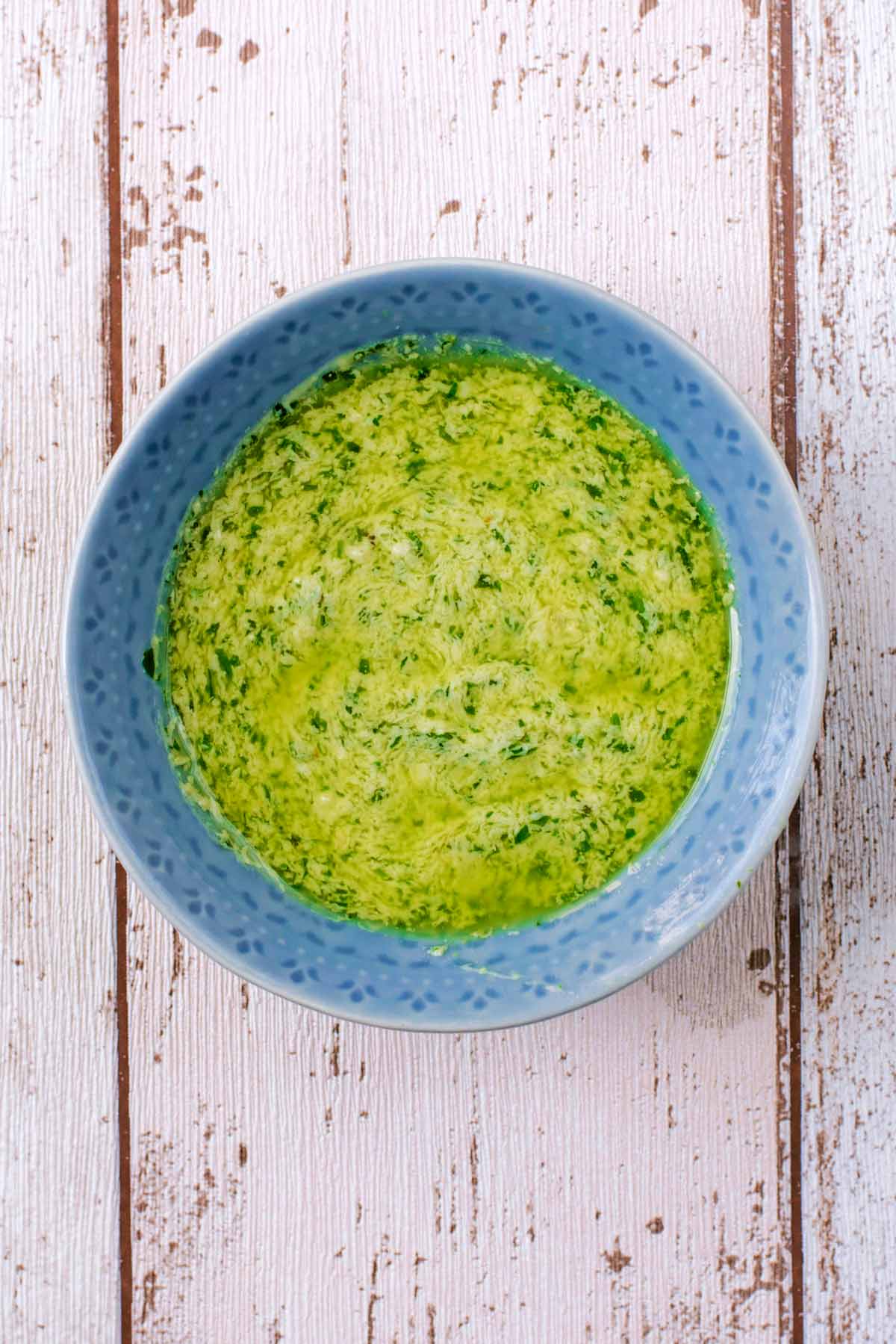 a green and yellow coloured sauce in a small blue bowl.