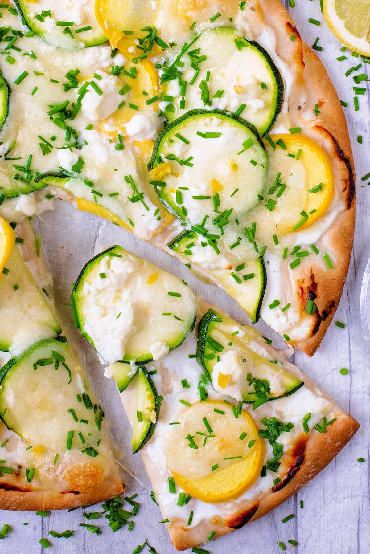 A green and yellow courgette pizza with a slice cut out.