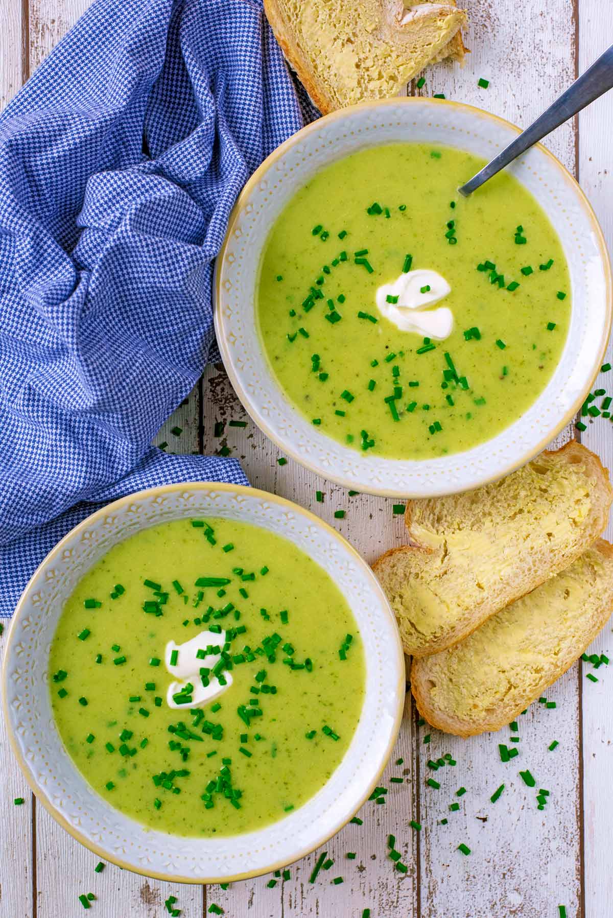 Two bowls of courgette soup with some buttered bread.