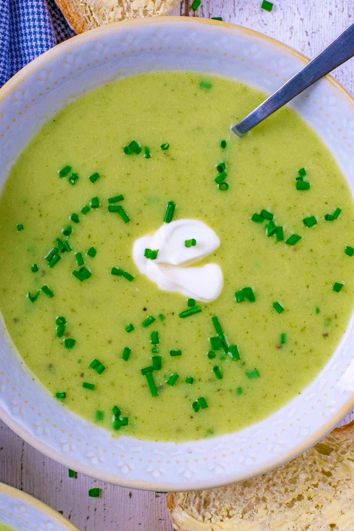 Courgette soup with a dollop of cream and a spoon.