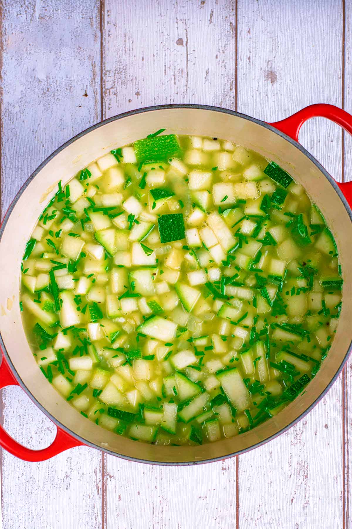 Chopped courgette, onions and stock in a larger red pan.