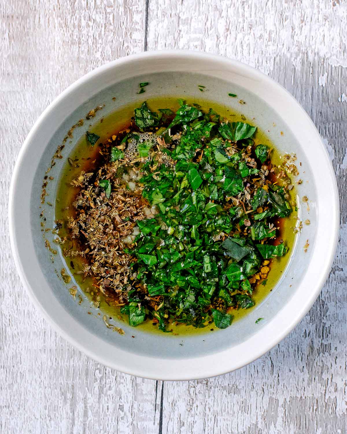 A small dish containing a mixture of oil, seasoning and herbs.