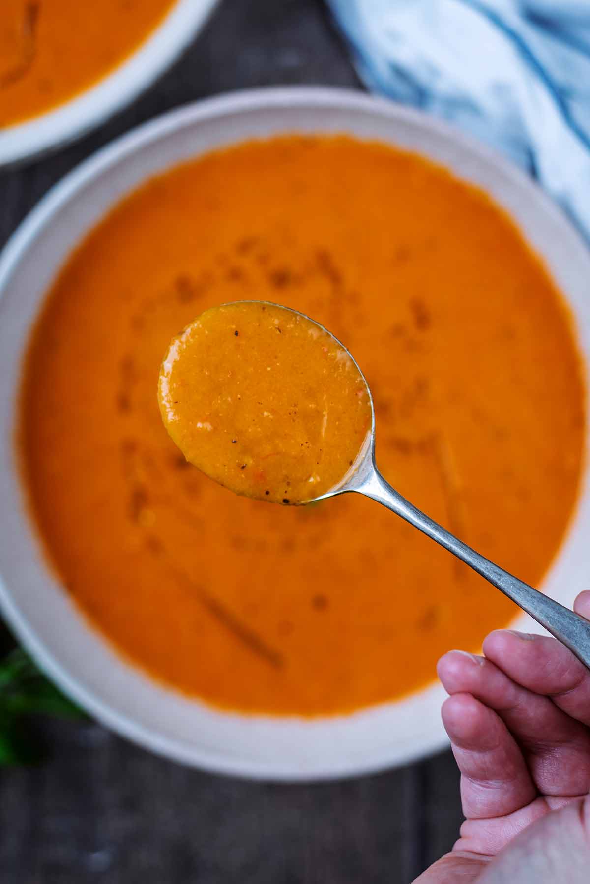 A spoon lifting soup from a bowl.