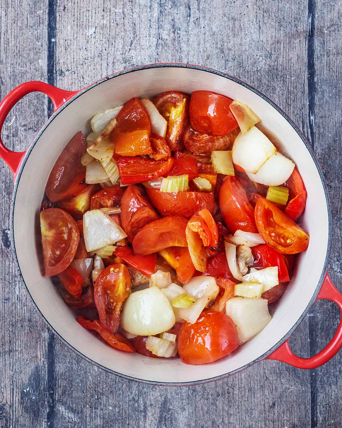 All the chopped vegetables in a large red pan.