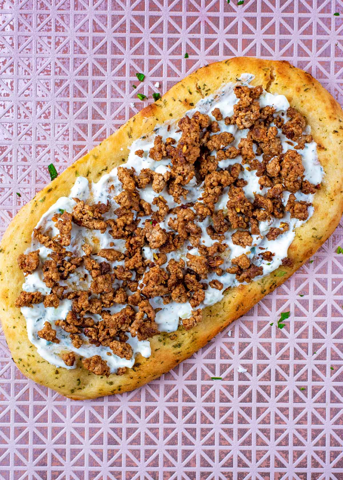 A flatbread topped with tzatziki and minced lamb.