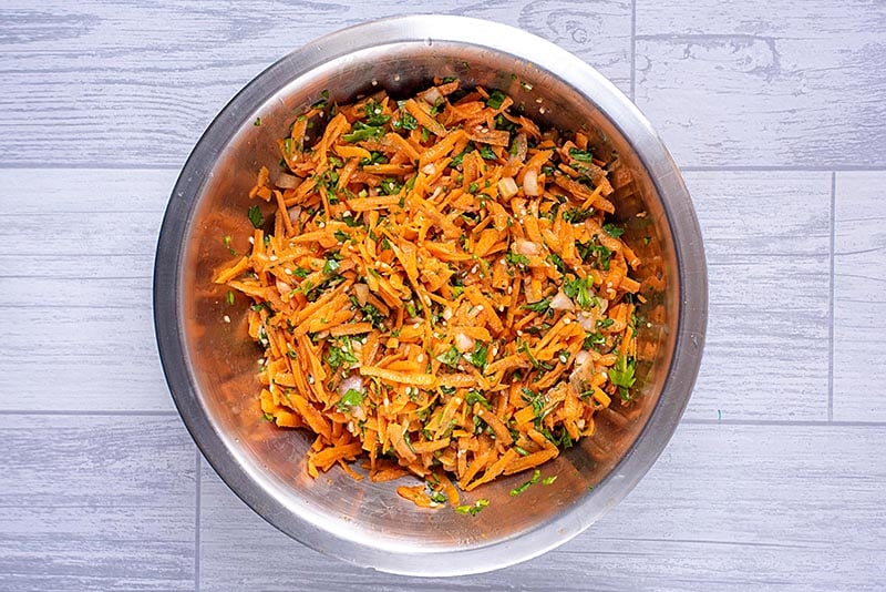 A large metal bowl full of carrot and coriander salad.