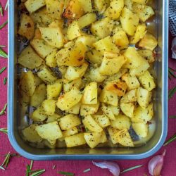 A roasting tin containing cubes of roasted potato.