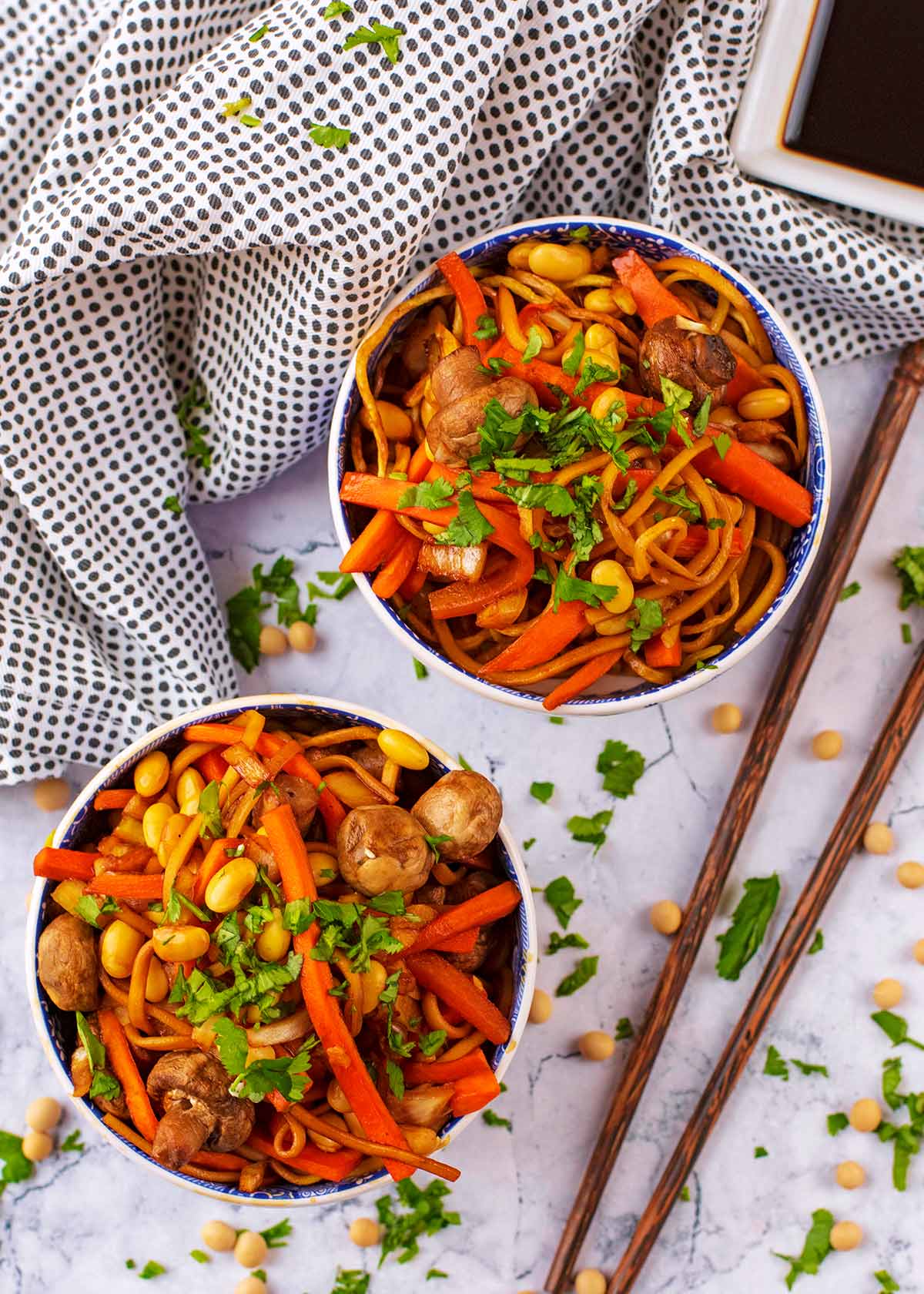 Two bowls of Chinese Noodles with chopsticks and soy sauce.