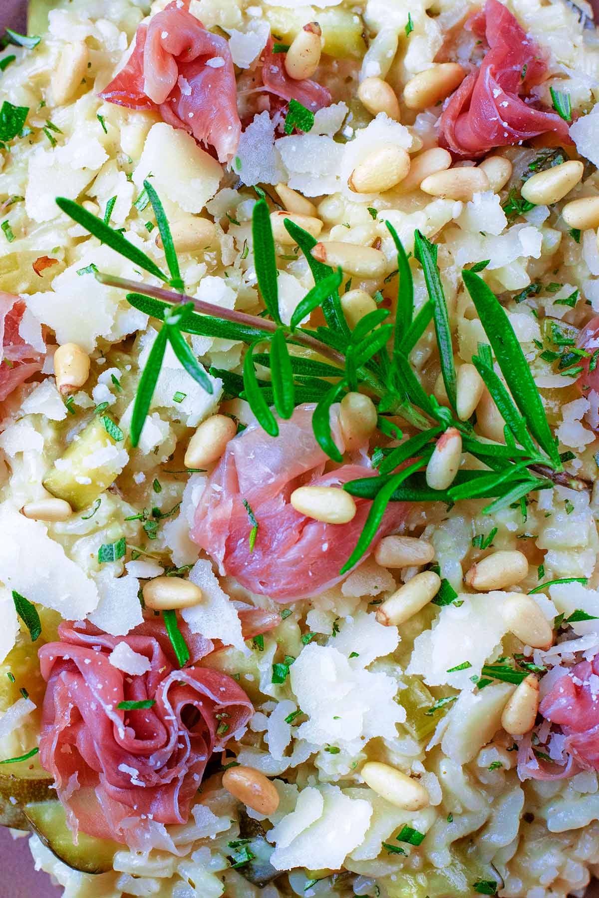 A sprig of rosemary and some curled up Parma ham sat upon courgette risotto.