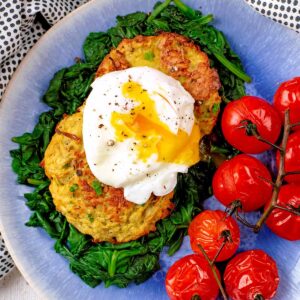 Oven baked hash browns with a poached egg on a bed of cooked spinach.