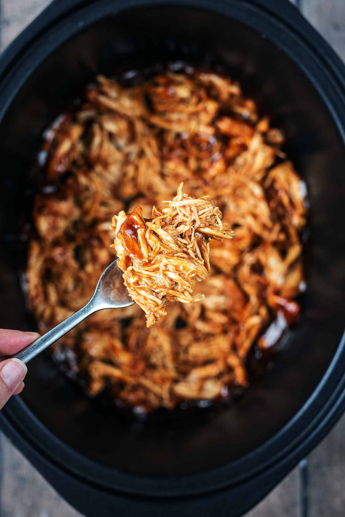 A ford liftin pulled chicken from a slow cooker pot.