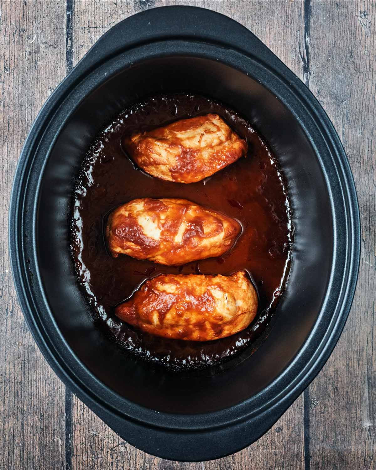 The cooked barbecue chicken in the slow cooker bowl.