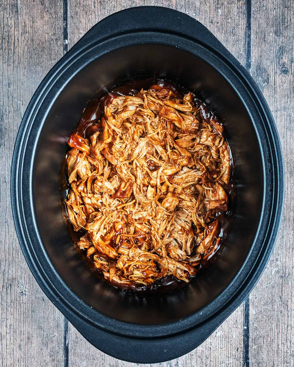The shredded chicken in the slow cooker bowl.