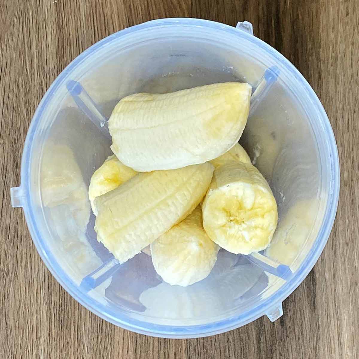Broken peeled bananas in a blender jug.