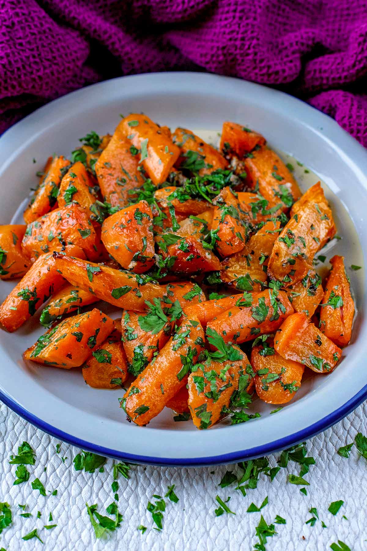 Carrots and herbs in a blue rimmed white bowl.